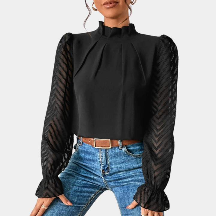 Zwarte damesblouse met lange doorschijnende mouwen en hoge hals, gecombineerd met blauwe jeans. Elegante mode, trendy kledingstijl.