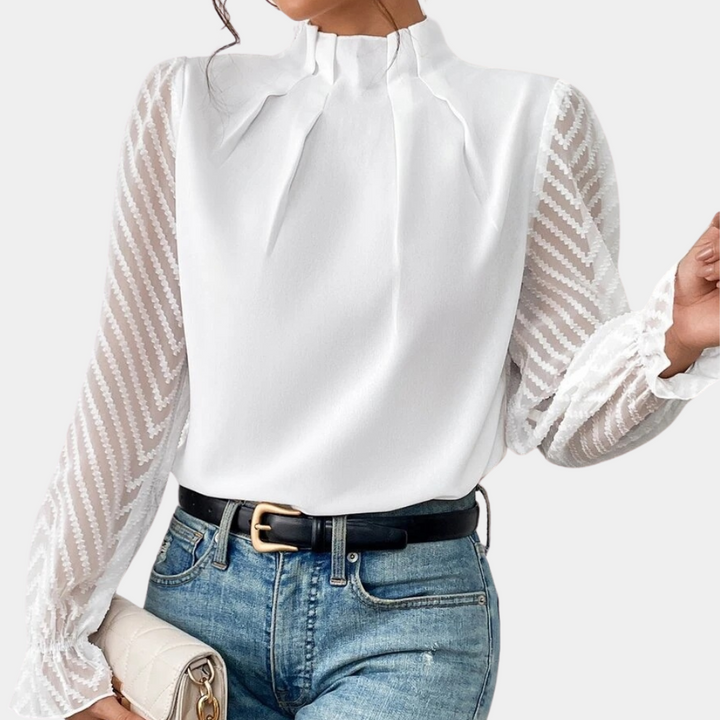 Witte blouse met transparante mouwen en zigzagpatroon, gedragen met blauwe jeans en zwarte riem. Elegante damesmode, trendy outfit.