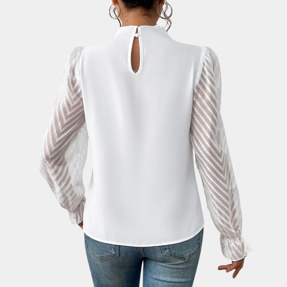 Vrouw in witte blouse met transparante mouwen en zigzagpatroon, gecombineerd met blauwe jeans. Elegante damesmode, trendy kledingstijl.