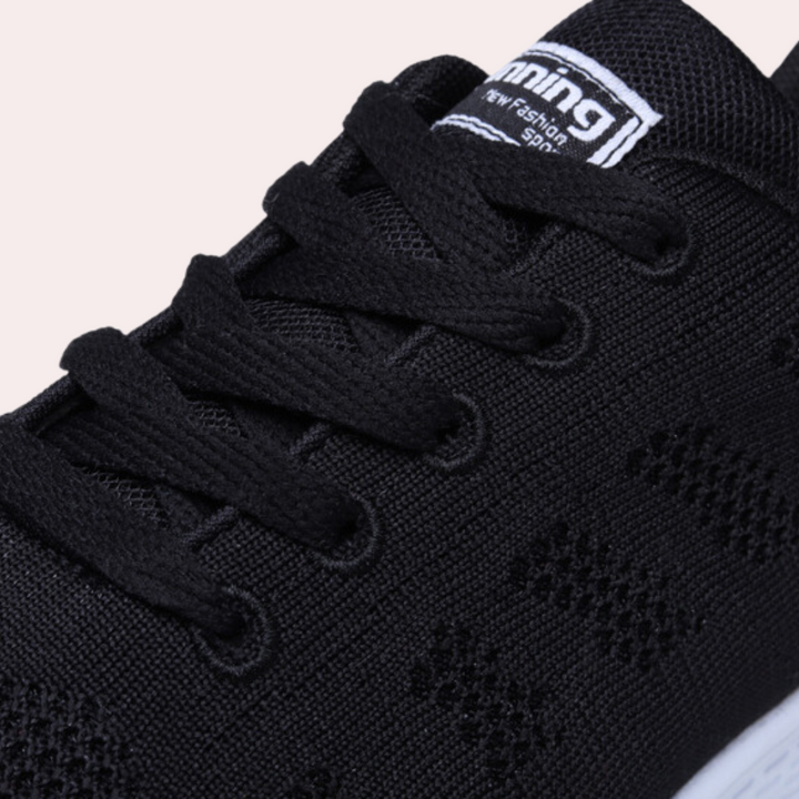 Zwarte sportschoen met veters, ademend mesh bovenwerk en witte zool. Ideaal voor hardlopen en casual gebruik. Comfortabele en stijlvolle sneaker.