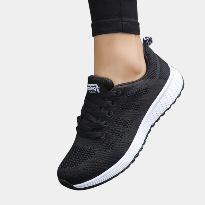 Zwarte dames sneaker met ademend mesh, witte zool en vetersluiting. Comfortabele sportschoen voor dagelijks gebruik. Perfect voor hardlopen en wandelen.