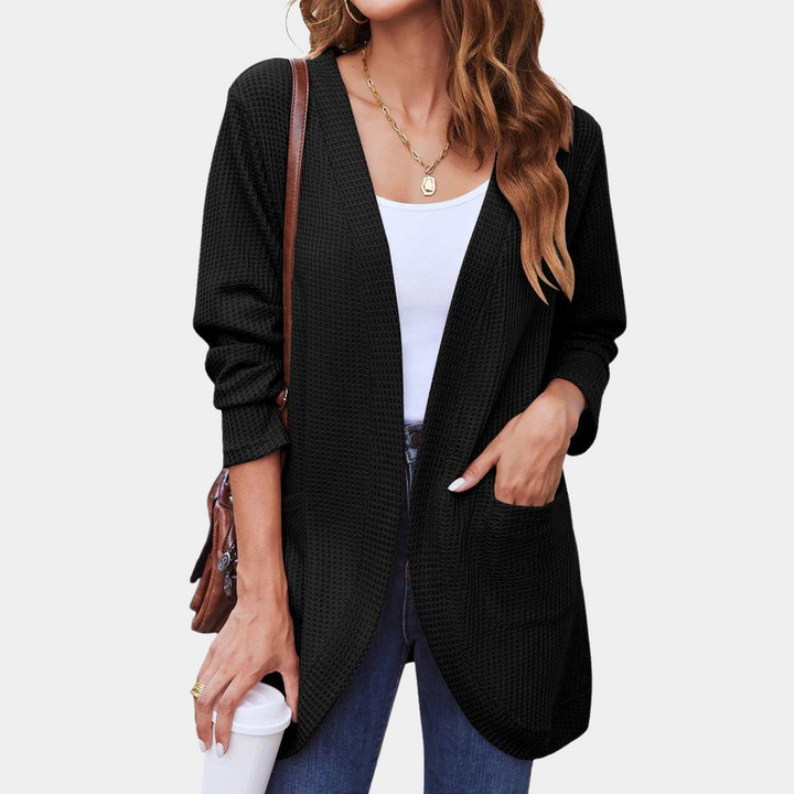 Vrouw draagt zwarte, lange cardigan met zakken, witte top en blauwe jeans. Casual damesmode, herfstkleding, stijlvolle outfit voor dagelijks gebruik.