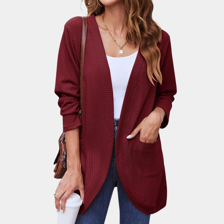 Vrouw draagt wijnrode cardigan met lange mouwen, gecombineerd met witte top en jeans. Casual damesmode, herfstkleding, trendy vest.