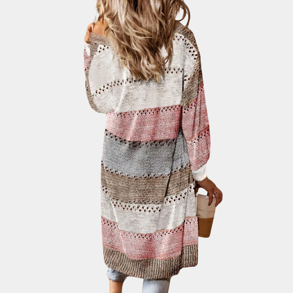 Vrouw in gestreepte, gebreide cardigan met roze, grijze en khaki tinten, houdt een koffiebeker vast. Casual damesmode, herfstkleding.
