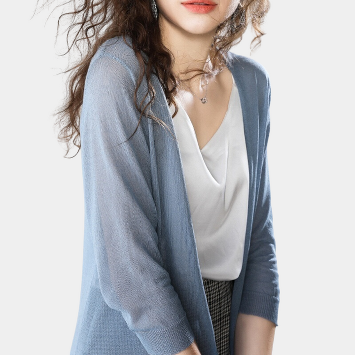 Vrouw in blauwe cardigan en witte blouse, modieuze kleding, casual stijl, trendy damesmode, elegante outfit, lange mouwen, stijlvolle look.
