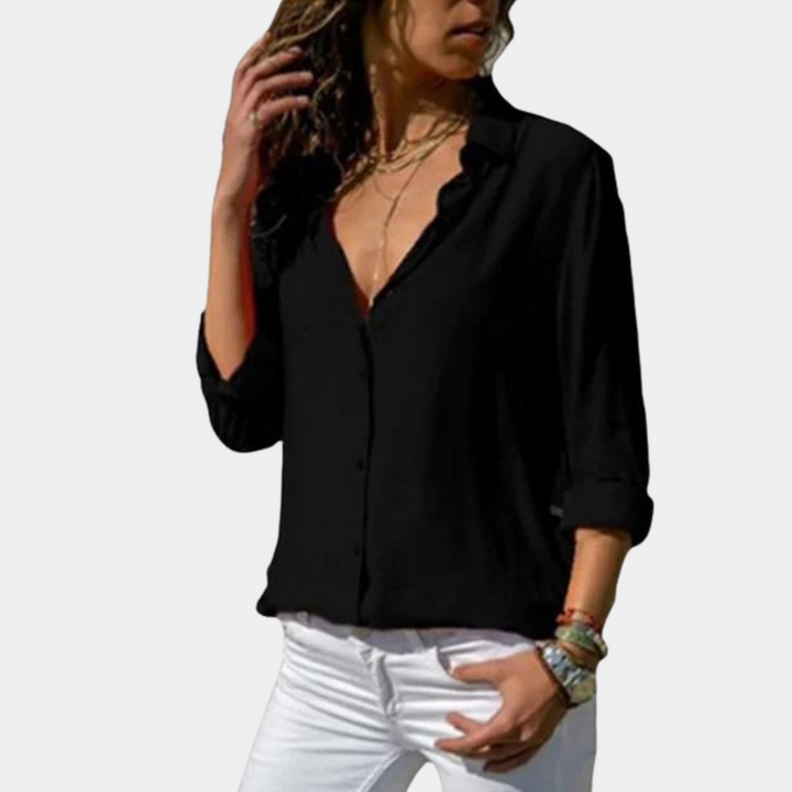 Zwarte damesblouse met lange mouwen, open kraag en knoopsluiting, gedragen met witte broek. Stijlvolle casual outfit voor dames.