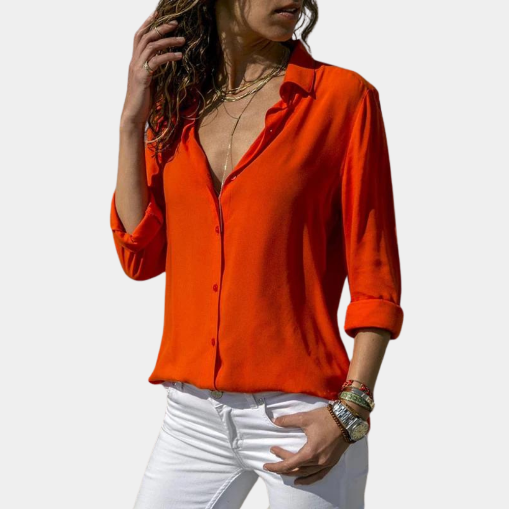 Oranje damesblouse met lange mouwen, diepe V-hals en opgerolde mouwen, gecombineerd met witte broek. Perfect voor casual en stijlvolle outfits.