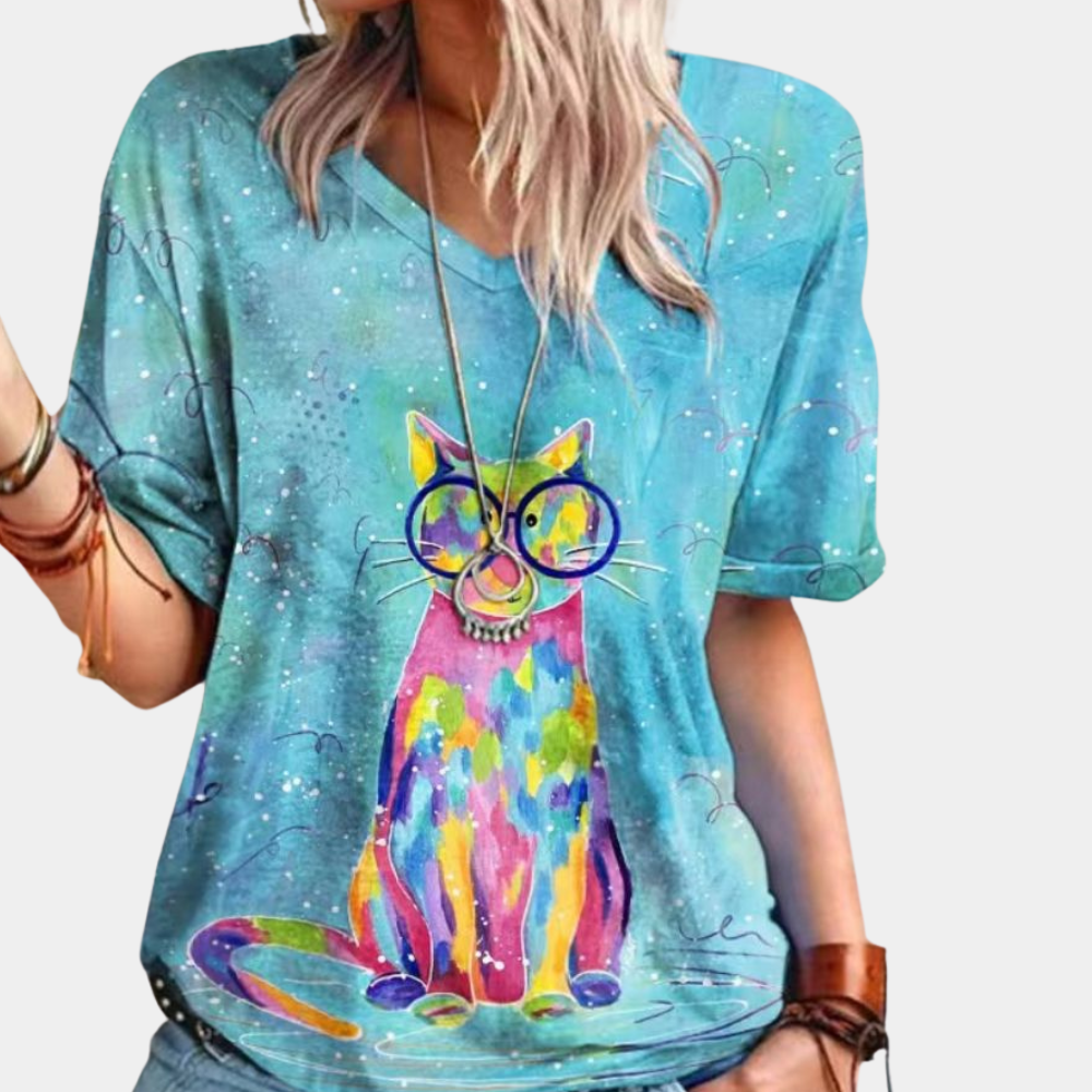 Vrouw draagt blauw T-shirt met kleurrijke kattenprint en bril, casual mode, trendy dameskleding, artistiek ontwerp, zomeroutfit.