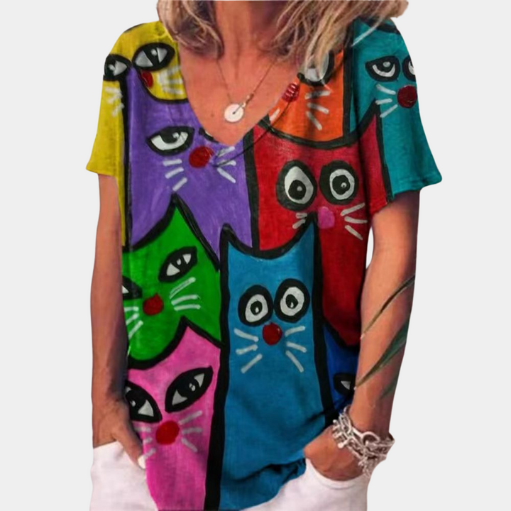 Vrouw draagt kleurrijk T-shirt met cartoon kattenprint in rood, blauw, groen en roze. Mode, dameskleding, casual stijl, opvallend ontwerp.