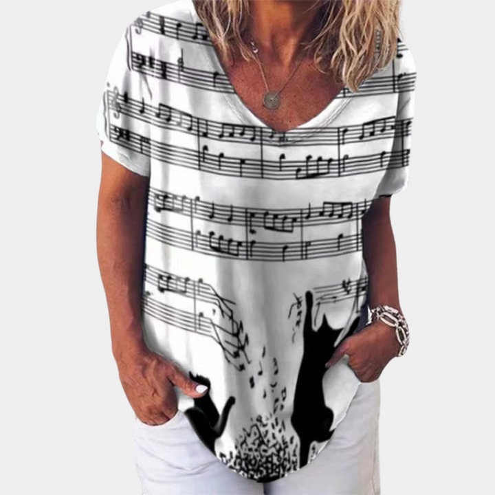 Vrouw draagt wit T-shirt met muzieknoten en silhouetten van katten, casual mode, korte mouwen, ronde hals, trendy dameskleding.