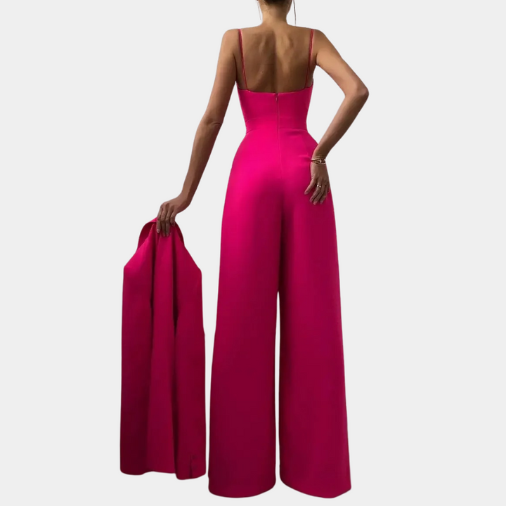 Vrouw in roze jumpsuit met wijde pijpen, houdt bijpassende blazer vast. Elegante damesmode, trendy avondkleding, stijlvolle outfit.