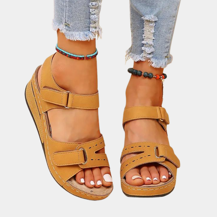 Bruine sandalen met klittenbandsluiting, gedragen met gescheurde jeans en kleurrijke enkelbandjes. Comfortabele zomerschoenen voor dames.