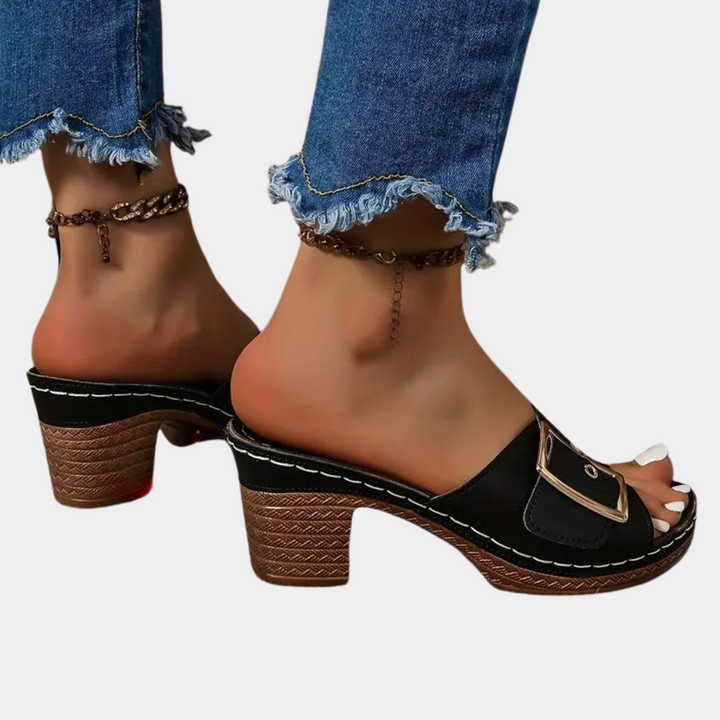 Zwarte leren sandalen met blokhak en gesp, gedragen met gerafelde jeans. Trendy damesmode, comfortabele zomerschoenen, casual stijl.
