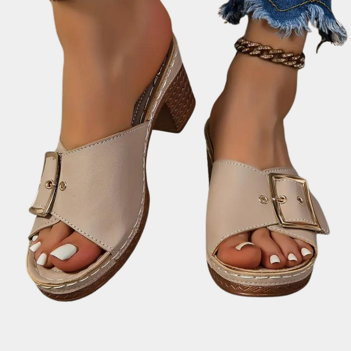 Beige damesmuiltjes met blokhak, open teen en grote gesp. Modieuze zomerschoenen, ideaal voor casual en trendy outfits.
