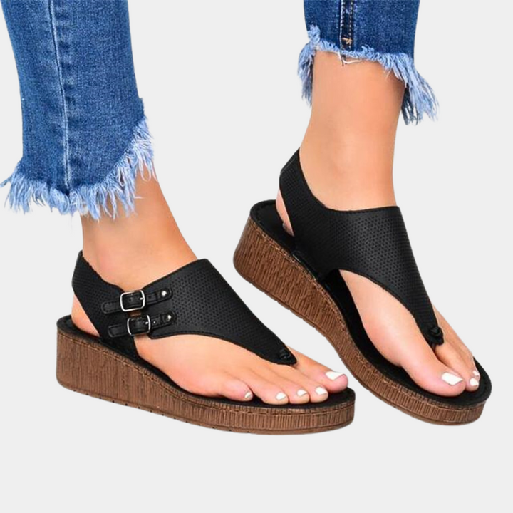 Zwarte sandalen met sleehak, open teen en gespsluiting, gedragen met gerafelde jeans. Comfortabele zomerschoenen voor dames.