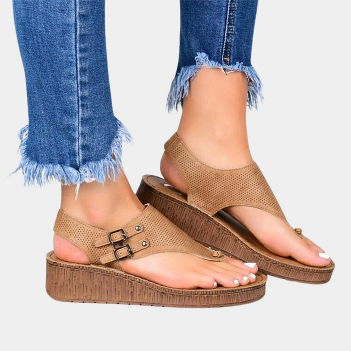 Bruine sandalen met sleehak en gespen, gedragen met gerafelde jeans. Comfortabele zomerschoenen voor dames, modieus en casual.