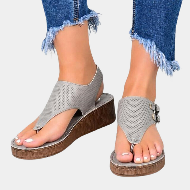 Grijze dames sandalen met sleehak, open teen en gespsluiting, gedragen met gerafelde jeans. Comfortabele zomerschoenen voor casual outfits.