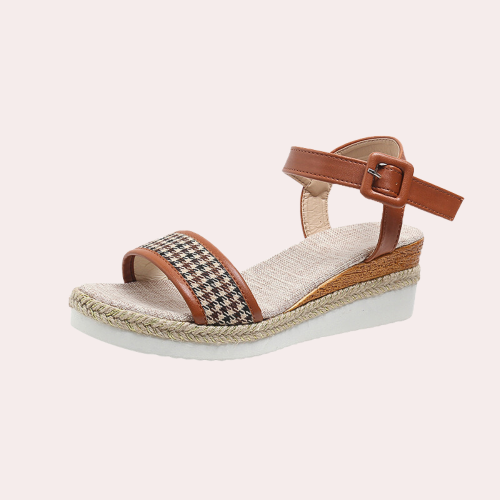 Bruine dames sandaal met sleehak, geweven patroon, verstelbare enkelband en witte zool. Perfect voor zomerse outfits en casual stijl.