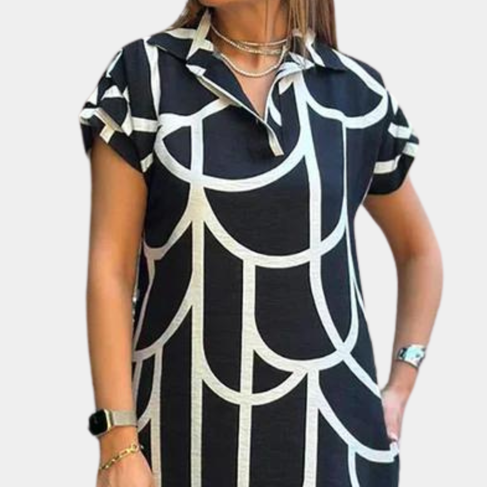 Vrouw in zwart-witte jurk met geometrisch patroon, korte mouwen en kraag. Draagt horloge en armband. Modieuze dameskleding.
