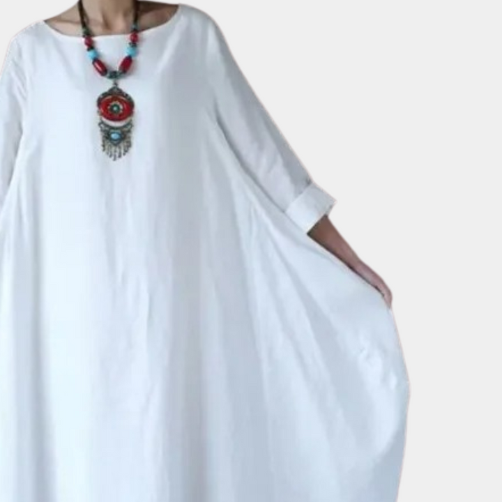 Witte, losse maxi-jurk met driekwartsmouwen en kleurrijke etnische ketting. Perfect voor zomerse dagen en boho-stijl liefhebbers.