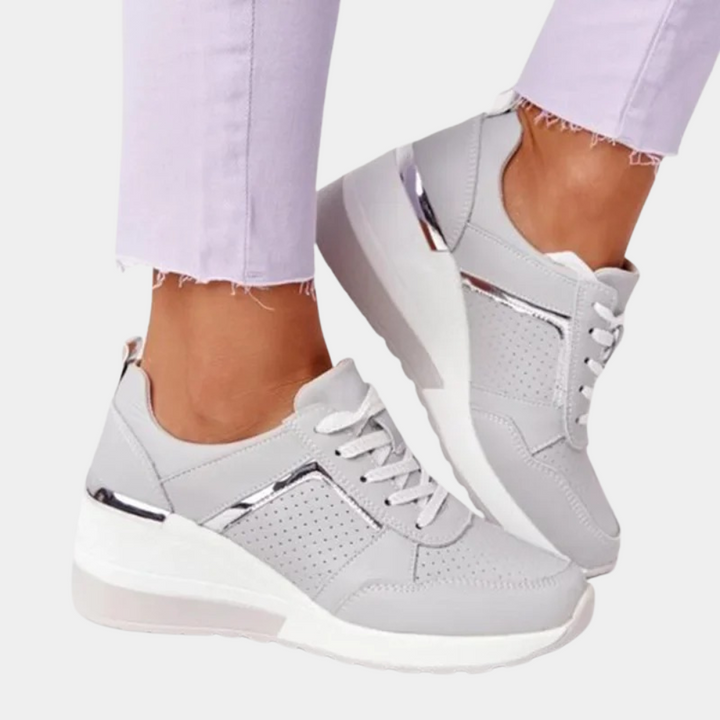 Witte dames sneakers met zilveren accenten, verhoogde zool en perforatiedetails. Modieuze en comfortabele schoenen voor dagelijks gebruik.