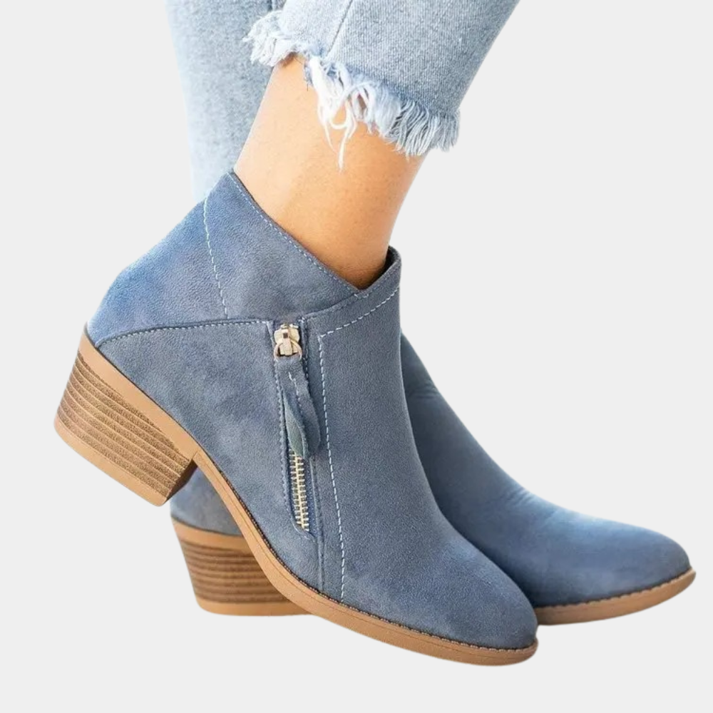 Blauwe suède enkellaarsjes met houten blokhak en ritssluiting, gedragen met lichtblauwe jeans. Trendy damesmode, comfortabele schoenen.