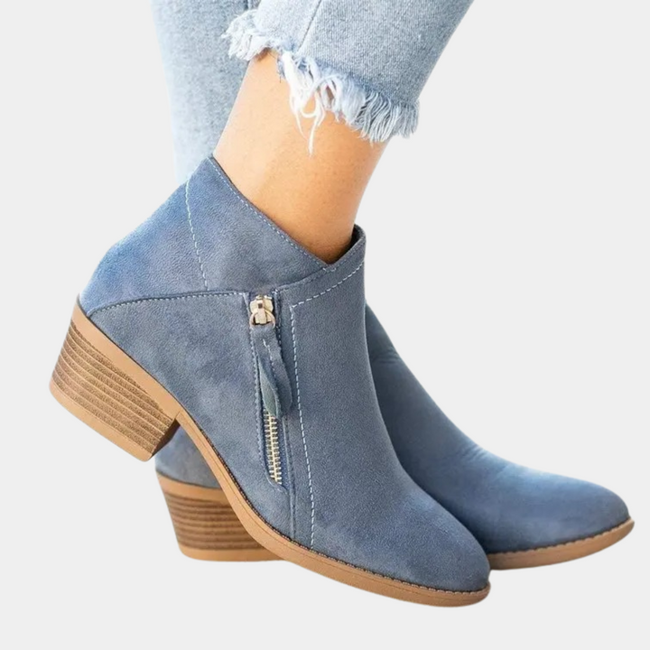Blauwe suède enkellaarsjes met houten blokhak en ritssluiting, gedragen met lichtblauwe jeans. Trendy damesmode, comfortabele schoenen.