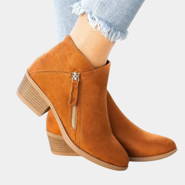 Oranje suède enkellaarsjes met rits en blokhak, gedragen met lichtblauwe jeans. Trendy damesmode, comfortabele herfst- en winterlaarzen.