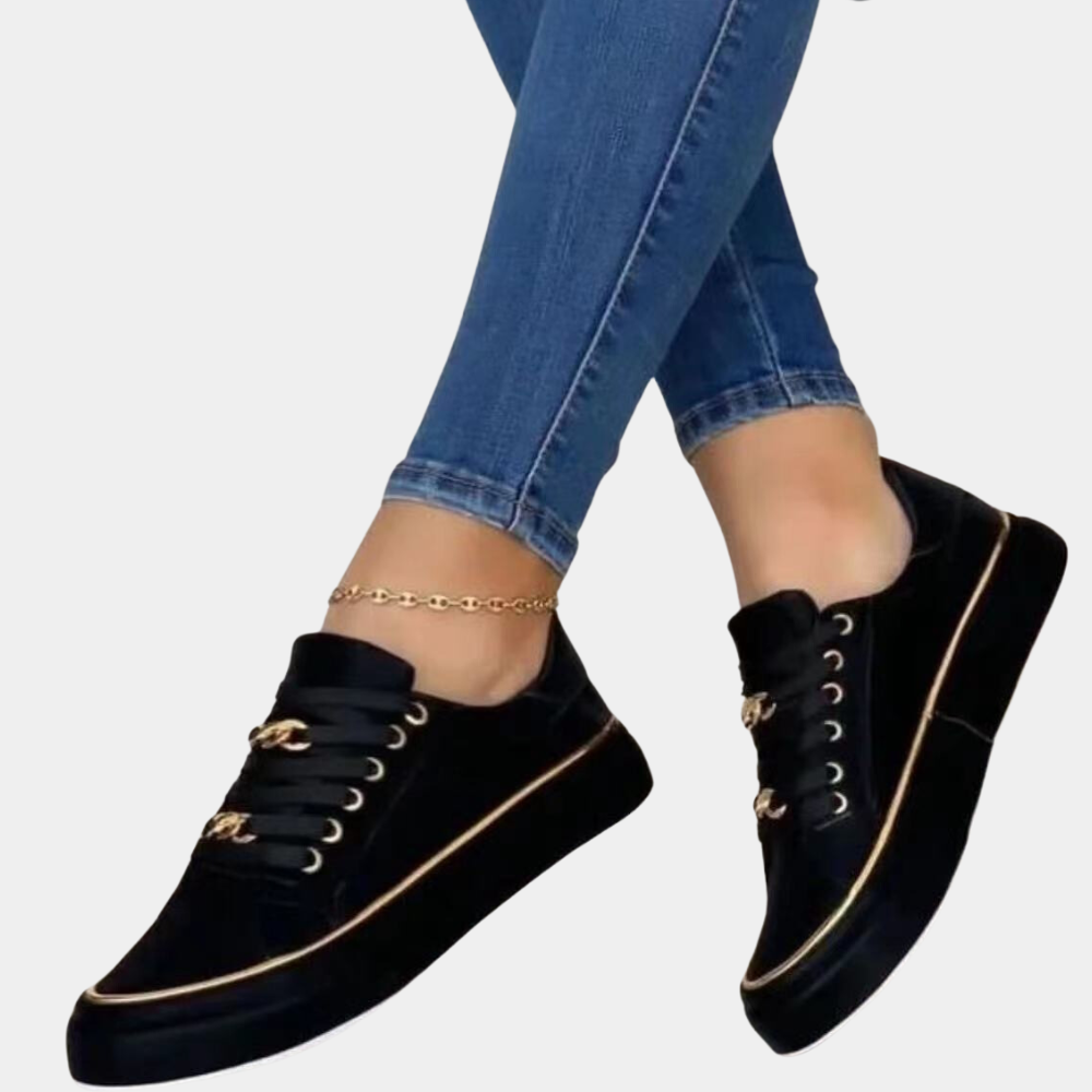 Zwarte sneakers met gouden details, gedragen met blauwe jeans. Stijlvolle damesmode, casual schoenen, trendy design, comfortabele pasvorm.