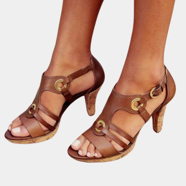 Bruine leren damessandalen met hoge hakken en open teen, voorzien van gouden gespen en kurken zool. Stijlvolle zomerschoenen voor dames.