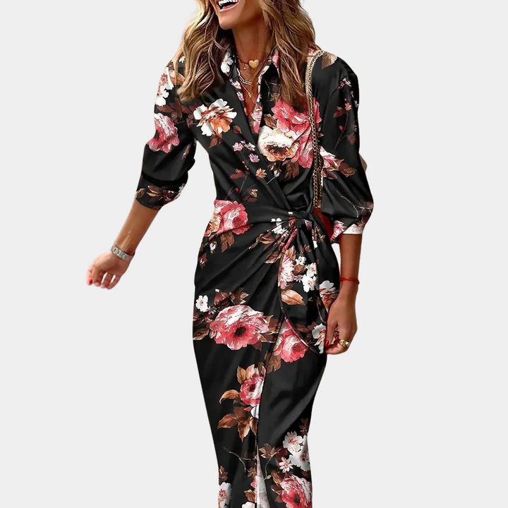 Vrouw in elegante zwarte bloemenjurk met lange mouwen, knoopdetail en kleurrijke bloemenprint. Perfect voor modieuze, stijlvolle gelegenheden.