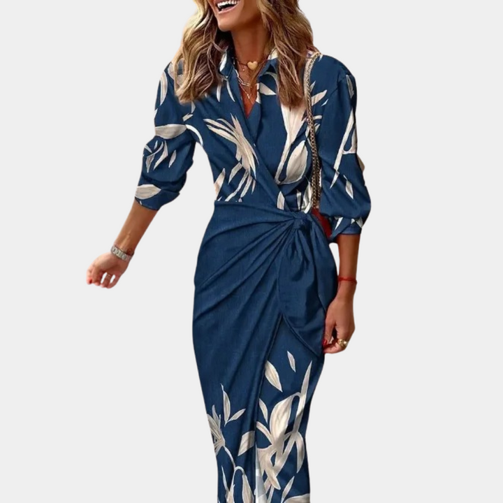 Donkerblauwe damesjurk met lange mouwen en witte bladprint, elegante wikkelstijl, ideaal voor casual en formele gelegenheden.