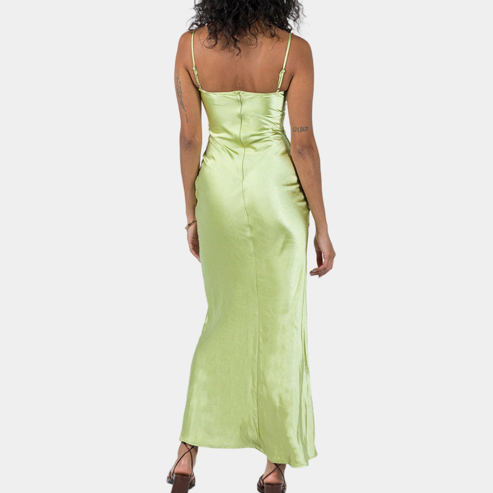 Vrouw in lange, lichtgroene satijnen jurk met spaghettibandjes, rugaanzicht. Elegante avondjurk, modieuze dameskleding.