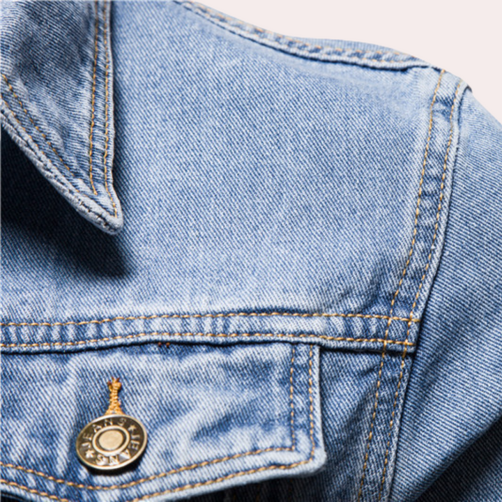 Blauwe denim jas met metalen knoop, close-up. Modieuze spijkerjas, casual kleding, hoogwaardige stof, trendy design.