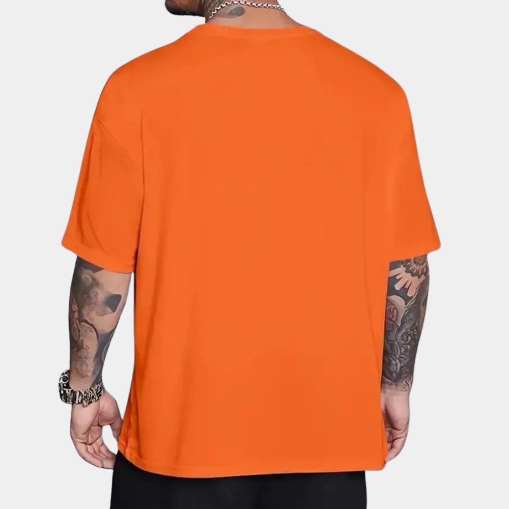Oranje T-shirt heren, korte mouwen, gedragen door getatoeëerde man. Casual mode, effen kleur, comfortabele pasvorm, trendy herenkleding.