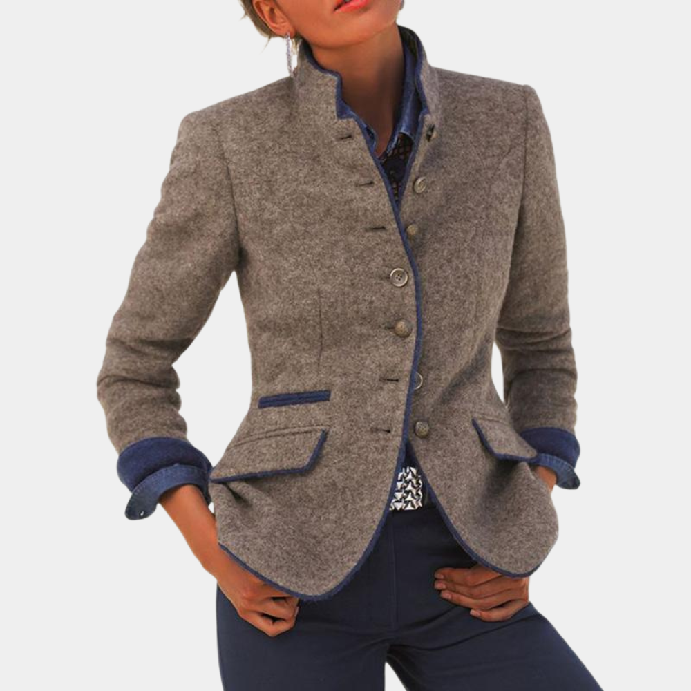 Grijze wollen damesblazer met opstaande kraag en knopen, gecombineerd met donkerblauwe broek. Stijlvolle herfstmode, elegante dameskleding.