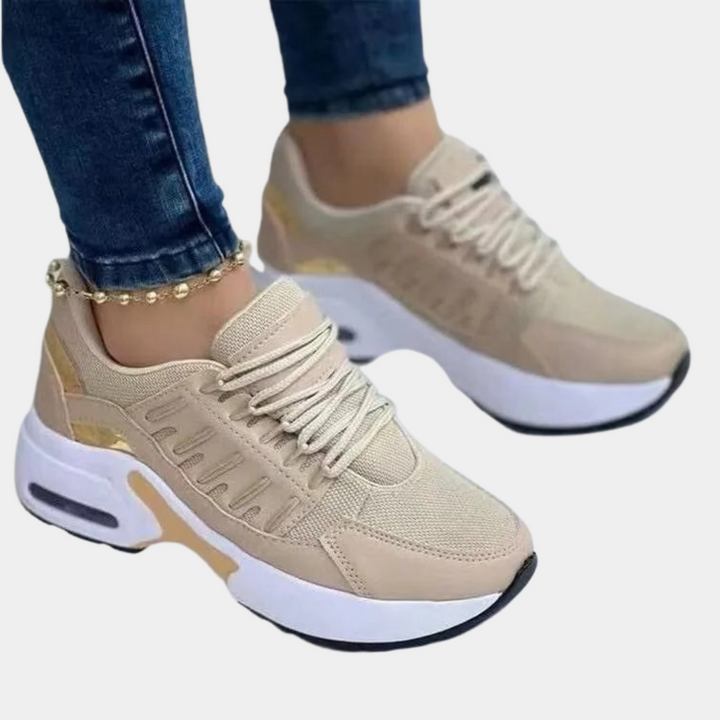 Beige dames sneakers met witte zool, gouden accenten en veters. Comfortabele sportieve schoenen, ideaal voor dagelijks gebruik en casual outfits.
