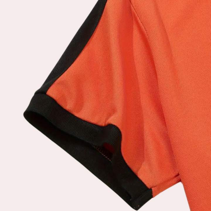 Oranje poloshirt met zwarte mouwboord, sportief design, ademende stof. Perfect voor casual en sportieve gelegenheden. Unisex kleding.