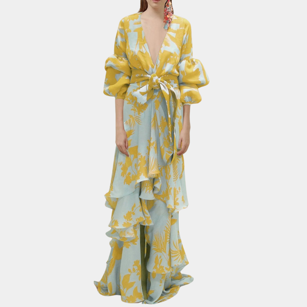 Vrouw in elegante gele en blauwe bloemenjurk met diepe V-hals en pofmouwen. Perfect voor zomerfeesten. Trendy damesmode, bohemian stijl.