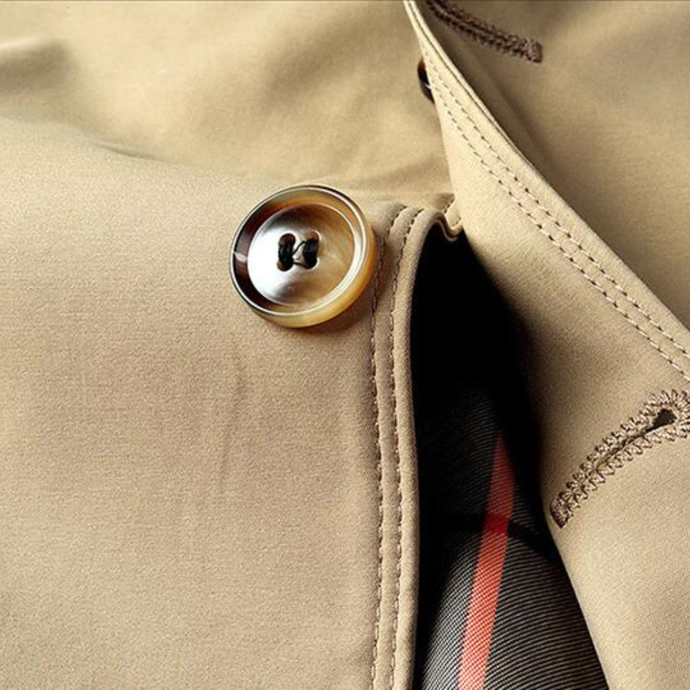 Beige trenchcoat met knoopdetail en gestreepte voering. Hoogwaardige stof, stijlvolle afwerking. Perfect voor modieuze herenkleding.