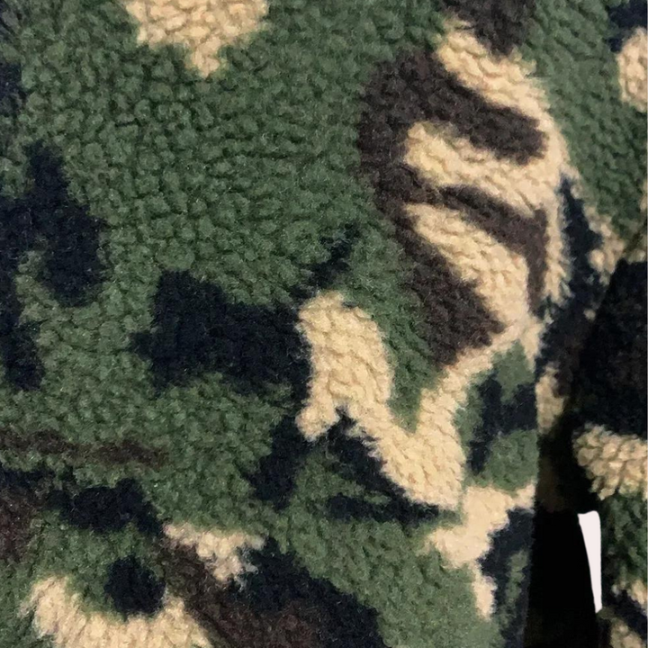 Groen en beige camouflage fleece stof, close-up textuur. Zachte, warme stof ideaal voor outdoor kleding en accessoires. Perfect voor herfst- en wintermode.