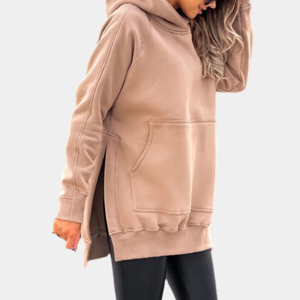 Vrouw in khaki oversized hoodie met capuchon en kangoeroezak, gecombineerd met zwarte legging. Comfortabele casual mode voor dames.