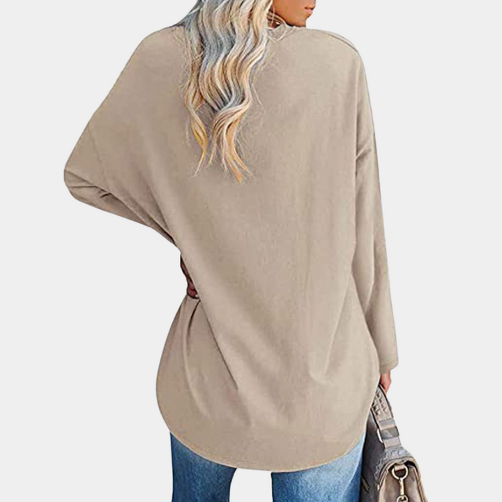 Vrouw in beige oversized trui met lange mouwen, casual stijl, gecombineerd met blauwe jeans. Perfect voor herfstmode en comfortabele outfits.