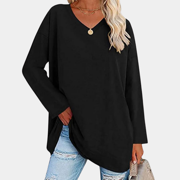 Vrouw in zwarte oversized trui met V-hals, gecombineerd met gescheurde jeans. Modieuze casual outfit, ideaal voor herfst- en winterseizoenen.