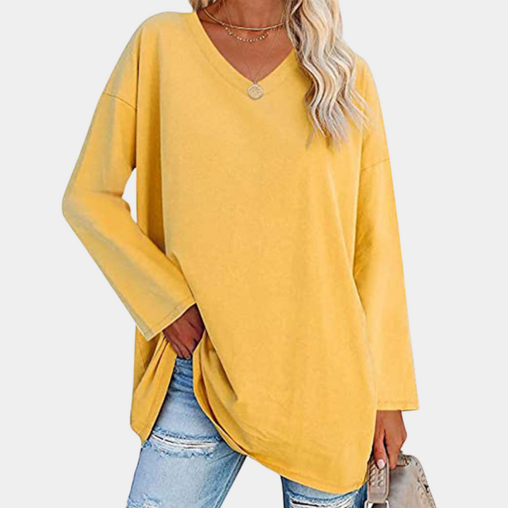 Vrouw in gele oversized trui met V-hals, gecombineerd met gescheurde jeans. Modieuze casual outfit, perfect voor lente- en herfstseizoenen.