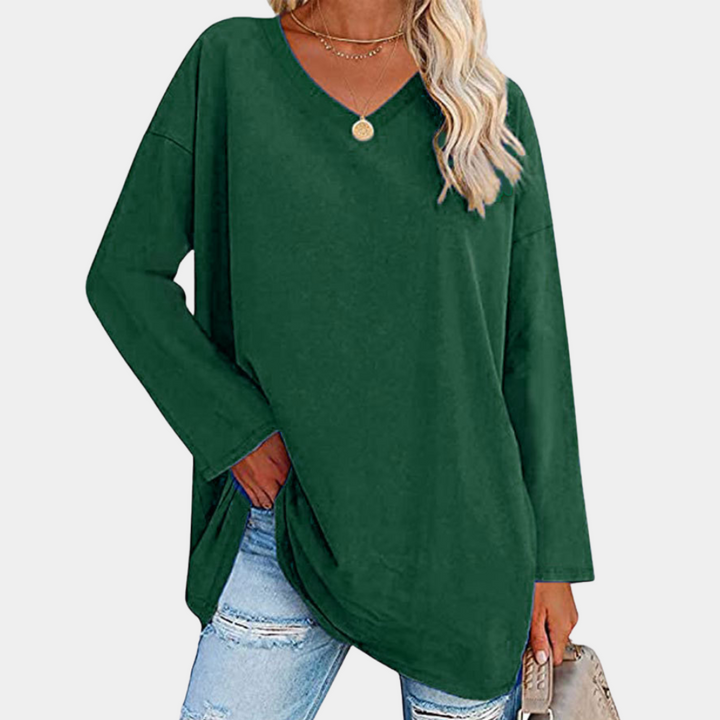 Vrouw in groene oversized trui met V-hals, gecombineerd met gescheurde jeans en gouden ketting. Modieuze casual outfit voor dames.