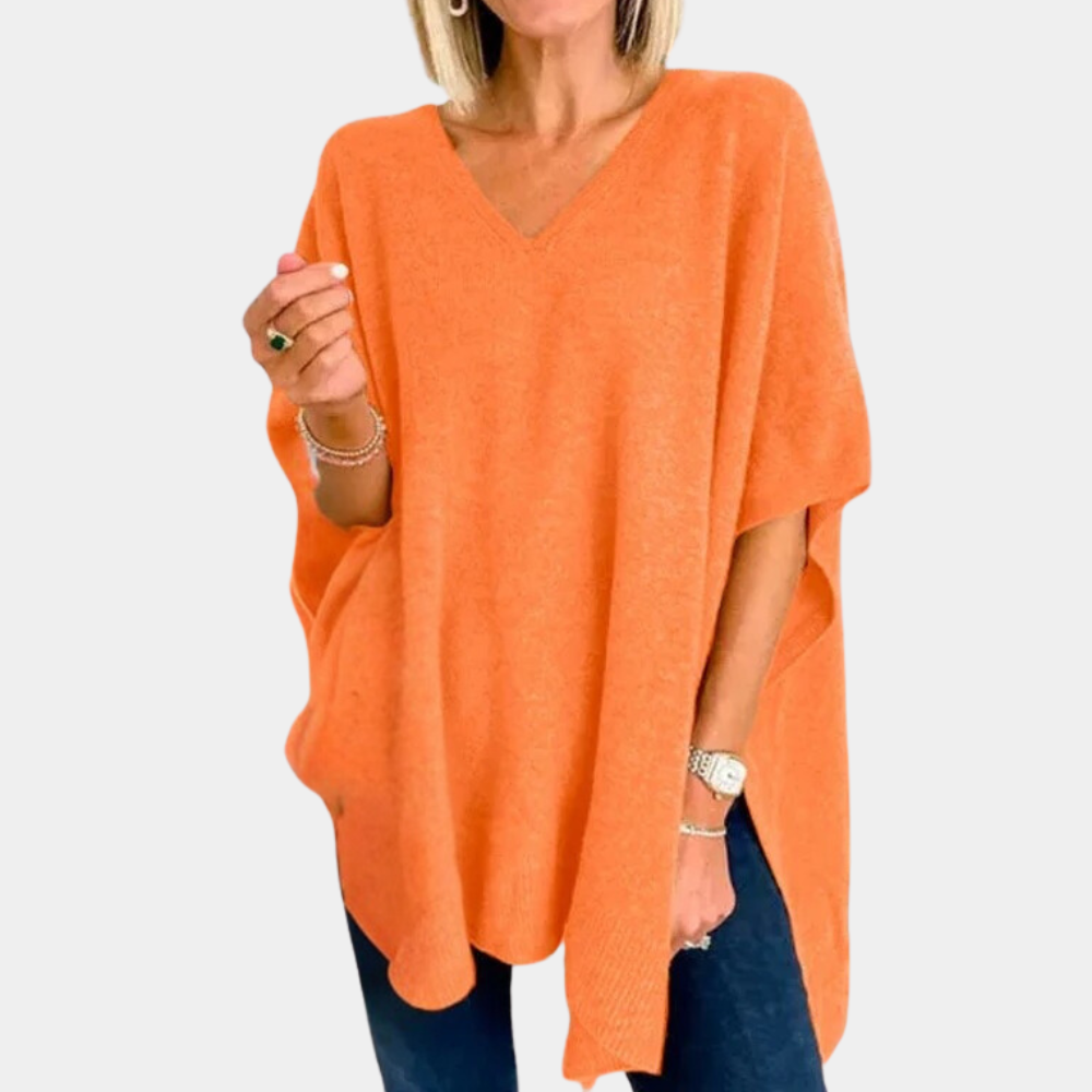 Oranje damesponcho met V-hals, gedragen door model. Stijlvolle, comfortabele poncho voor herfstmode. Perfect voor casual en chique outfits.