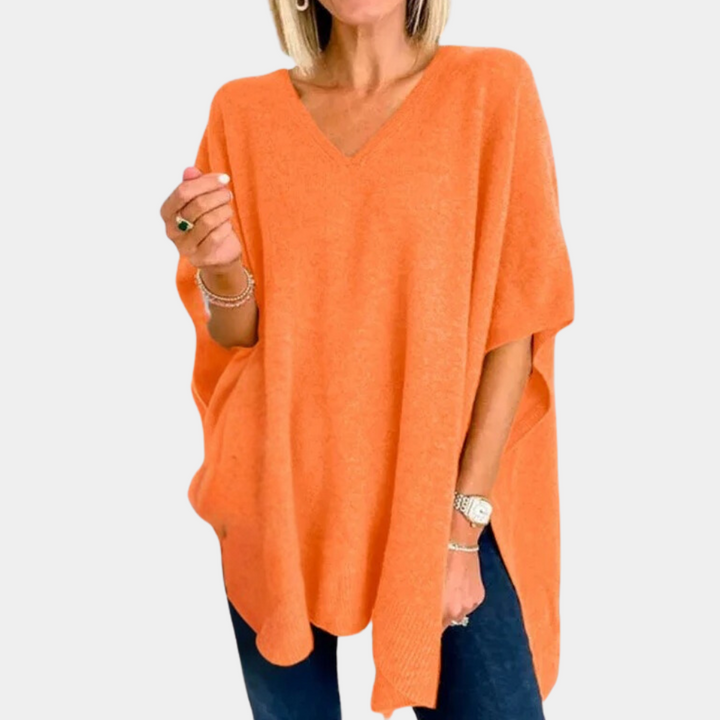 Oranje damesponcho met V-hals, gedragen door model. Stijlvolle, comfortabele poncho voor herfstmode. Perfect voor casual en chique outfits.
