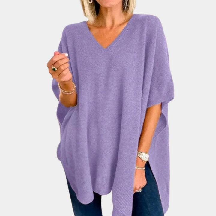 Vrouw draagt paarse oversized trui met V-hals, gecombineerd met blauwe jeans. Modieuze dameskleding, comfortabele herfst- en winteroutfit.