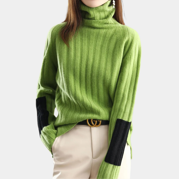 Groene geribbelde coltrui met zwarte elleboogstukken, gedragen door een model. Trendy damesmode, herfstkleding, stijlvolle trui.